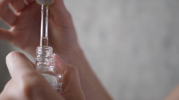 雌性手掌用移液器打开瓶子。天然面部血清。滴管上落下的基本液体滴。芳香疗法、精华和放松