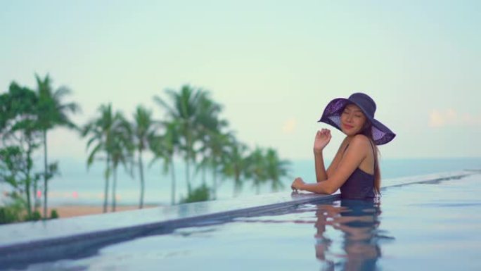 年轻的亚洲女性在室外游泳池周围放松快乐