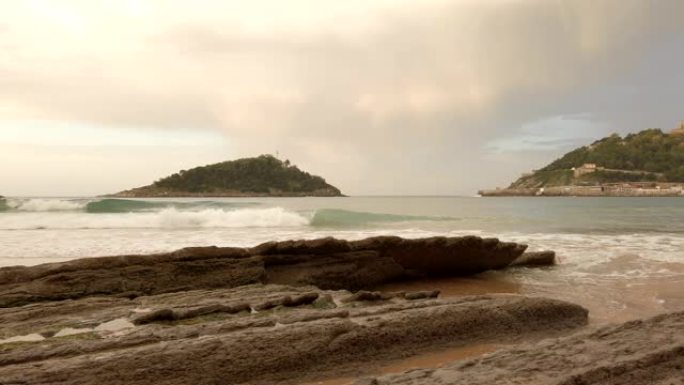 西班牙比斯开多诺斯蒂亚圣塞巴斯蒂安的日落。海滩、岩石、沙子和金色的云