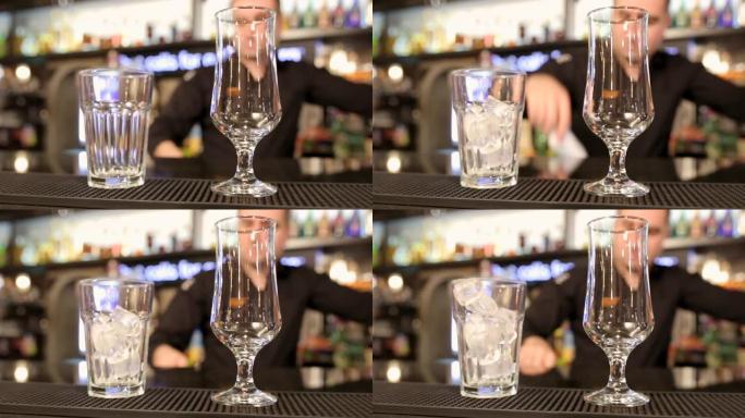 酒保将冰块放在夜总会酒吧柜台的水杯中