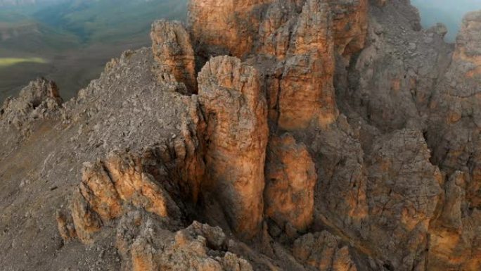 日落时无人机飞越尖锐的岩石露头的鸟瞰图。用于极端登山的陡峭的岩层山。飞行穿越旅行视频