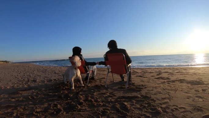 夫妇在冬天和狗一起在海滩上放松