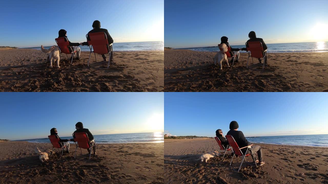 夫妇在冬天和狗一起在海滩上放松