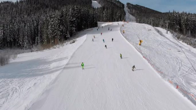 鸟瞰图许多滑雪者沿着滑雪场走下。无人机在滑雪者旁边低空飞行
