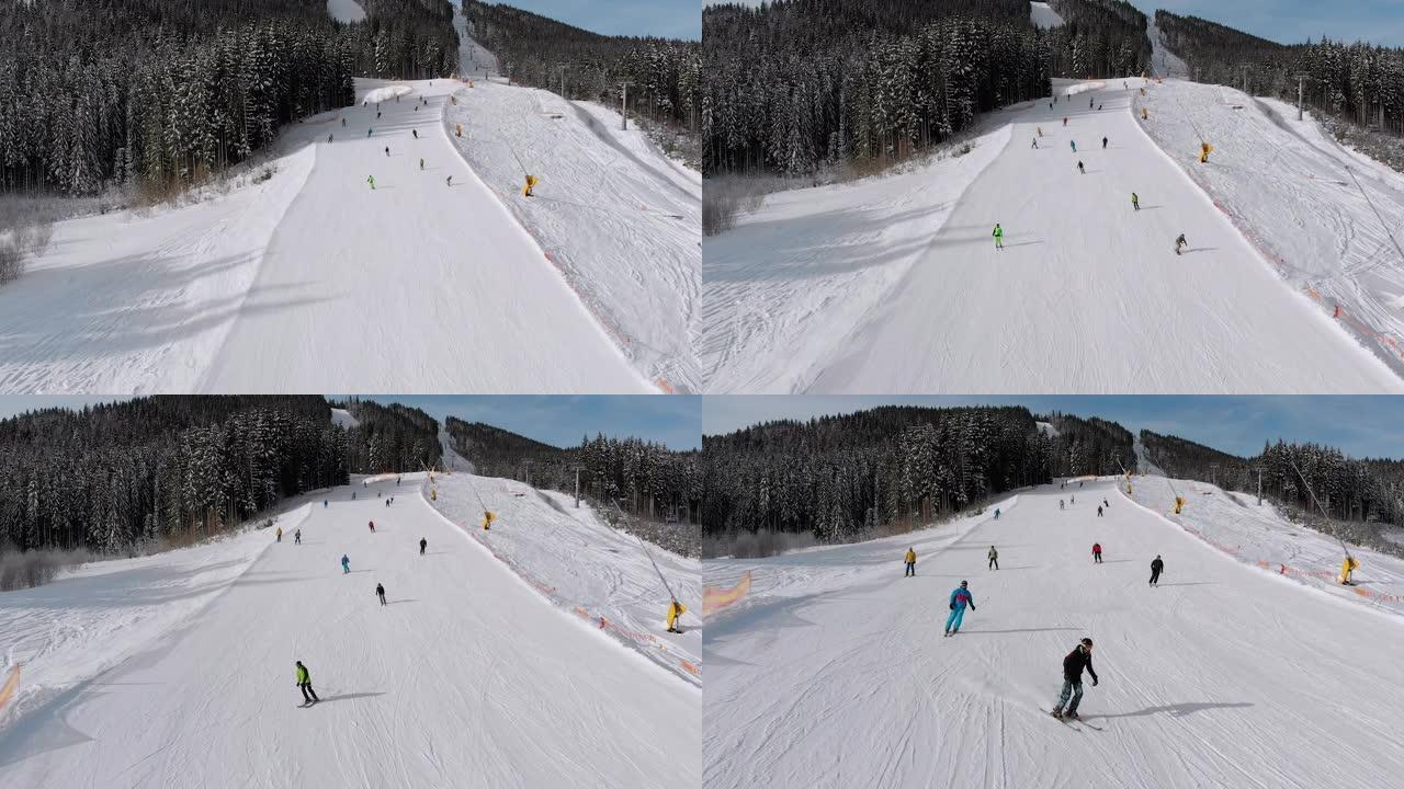 鸟瞰图许多滑雪者沿着滑雪场走下。无人机在滑雪者旁边低空飞行