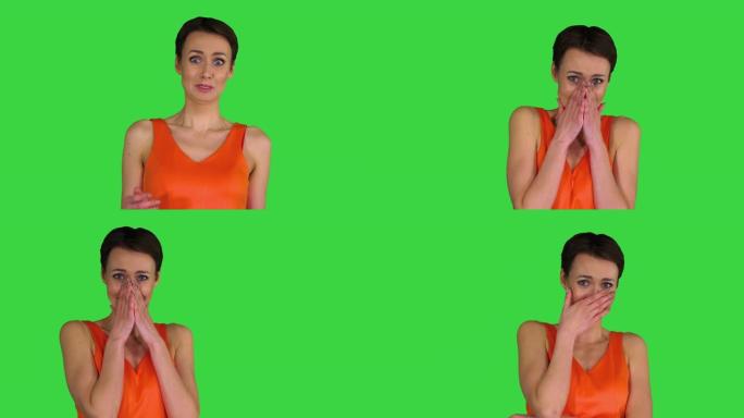 绿色屏幕上穿着橙色太阳裙的年轻女子震惊或惊讶，色键