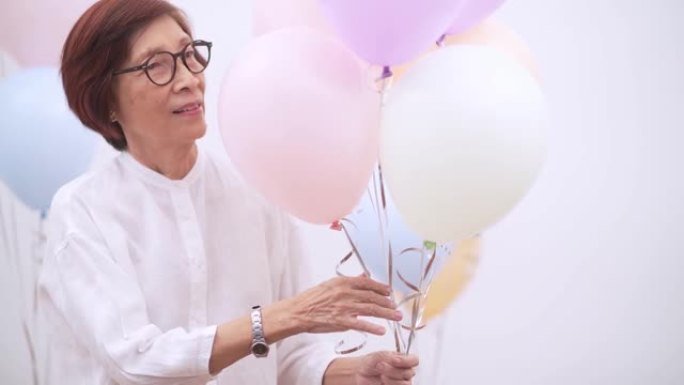 带气球的快乐亚洲高级女性。老年人生日或周年派对概念