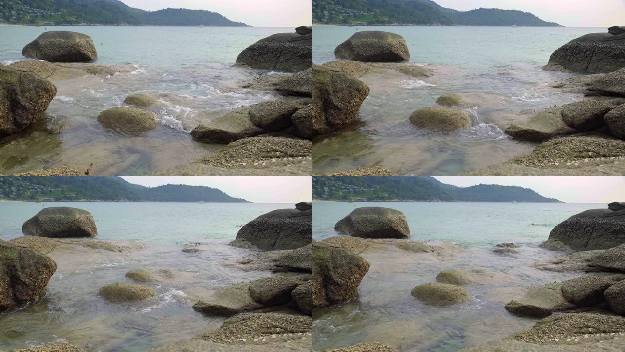 在被贝壳覆盖的石头上缓慢移动的波浪