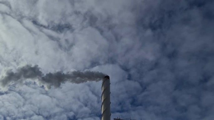 蓝天背景下烟囱冒出的白烟视图。生态学和温室效应概念。