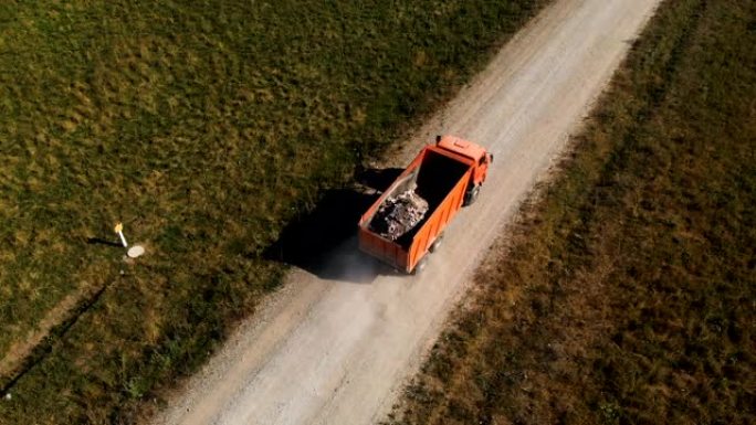 卡车的鸟瞰图。一辆自卸车，用卡车运送建筑碎屑石头和沙子，沿着乡间小路行驶。卡车运输物流货物交付