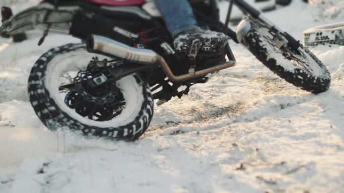 摩托车手在雪地里做轮胎倦怠，慢动作。专业摩托车手在日落时在雪地上漂移并打开摩托车。骑自行车的人在摩托