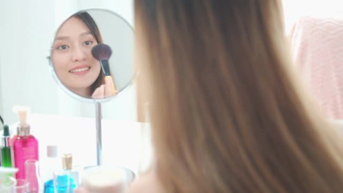 美丽的亚洲女人博主正在展示如何化妆和使用化妆品。在家里的镜子前。社交媒体概念上的商业在线影响者。