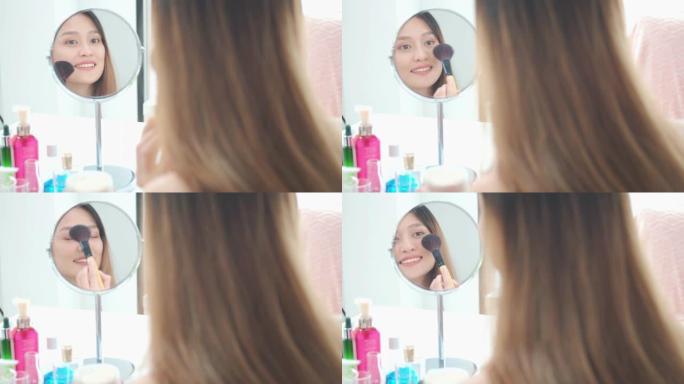 美丽的亚洲女人博主正在展示如何化妆和使用化妆品。在家里的镜子前。社交媒体概念上的商业在线影响者。