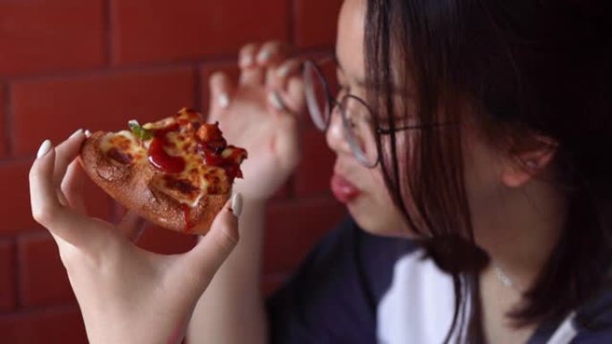 年轻的亚洲妇女从饮食中休息并选择比萨饼作为饭