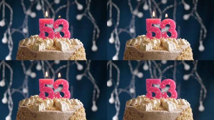 蓝色背景上有53号粉色蜡烛的生日蛋糕。蜡烛吹灭了。慢动作和特写视图