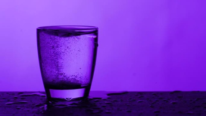 泡腾片溶解在一杯水-紫色背景，慢动作
