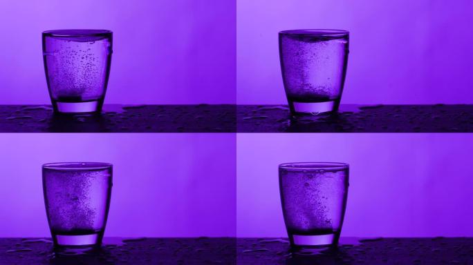 泡腾片溶解在一杯水-紫色背景，慢动作