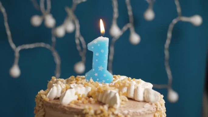 蓝色背景上有1个数字蜡烛的生日蛋糕。蜡烛吹灭了。慢动作和特写视图