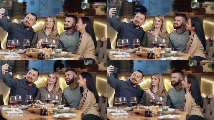 两对快乐的情侣在晚餐时使用智能手机合影。4k龙红相机