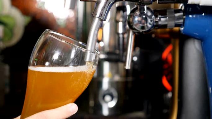 啤酒倒入和泡沫在玻璃上黑色酒吧背景关闭慢动作。金啤酒被倒入玻璃中，产生气泡和泡沫。高清视频