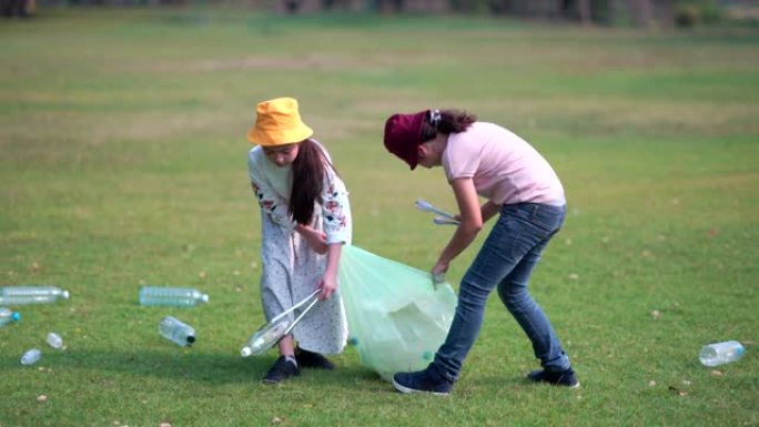 女孩和朋友帮助清理公园，捡起或垃圾收集地面上的垃圾