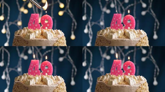 蓝色背景上有49号粉色蜡烛的生日蛋糕。蜡烛着火了。慢动作和特写视图