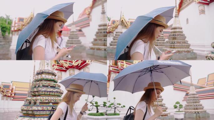 妇女和朋友在看地图。亚洲妇女在曼谷市享受曼谷Wat Pho的地标。亚洲妇女在雨天撑伞探索泰国的主要寺
