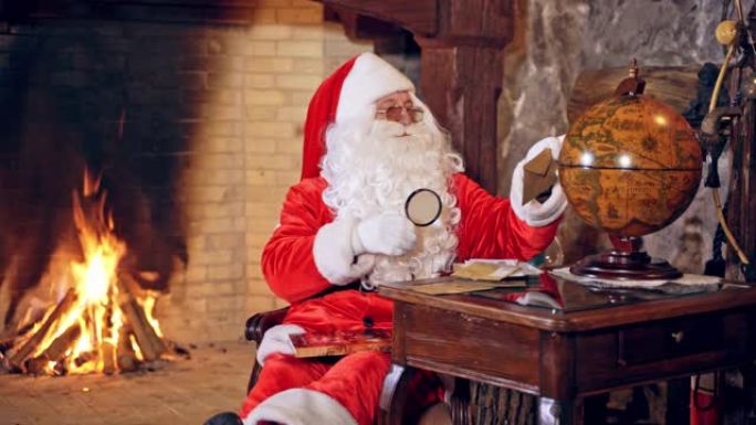 圣诞老人坐在桌子上装饰特别的房间里，手里拿着放大镜。