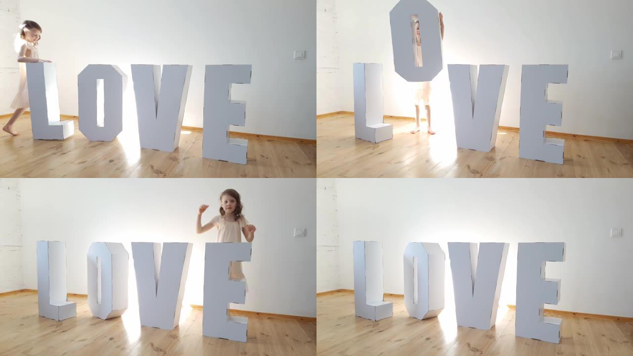 7岁的女孩玩大纸板3D站立字母从白色纸板形成单词爱在一个轻的背景。关系的概念
