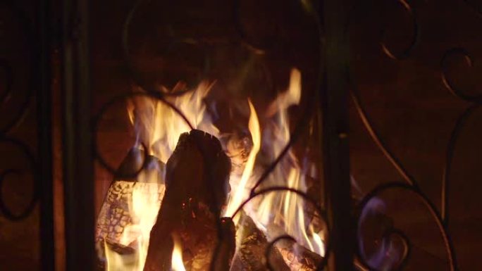 原木在带有装饰屏幕和炉排的老式石头壁炉中燃烧