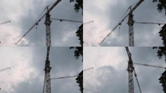 高鹤在建筑工地上工作，面对云层灰蒙蒙的天空。带起重机的建筑工地