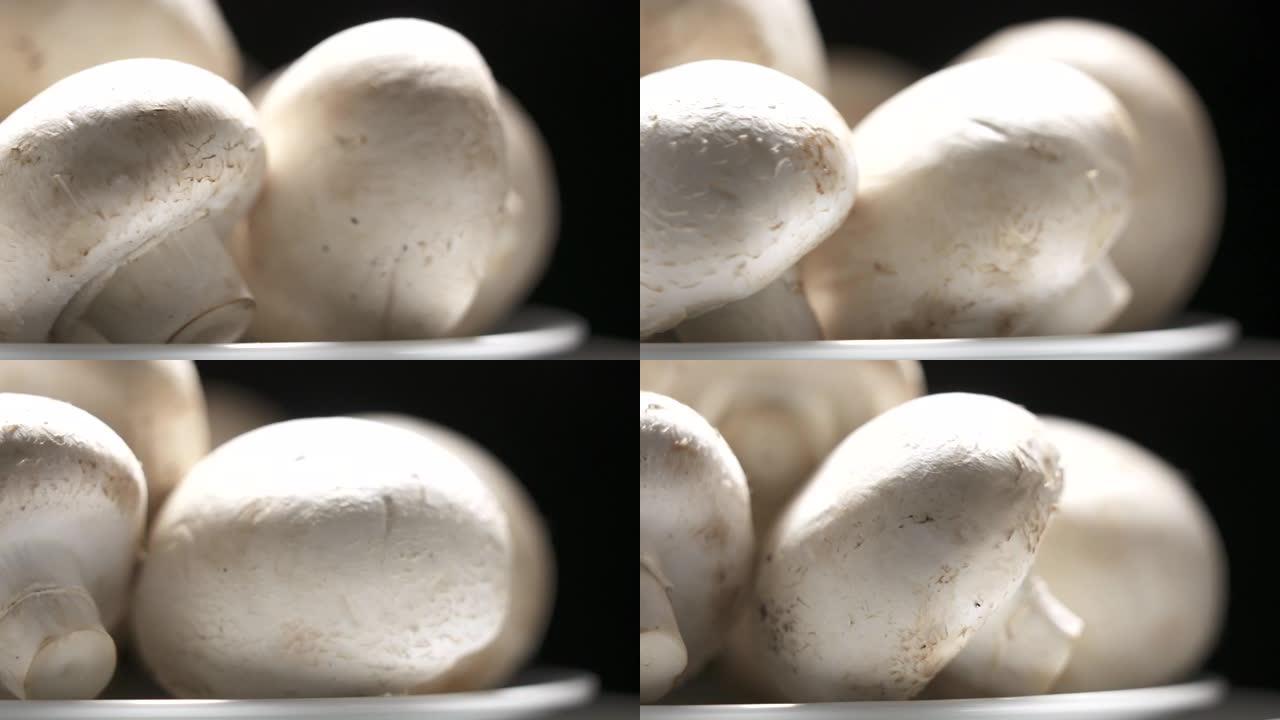 新鲜的生白色香菇在黑色背景上旋转特写。