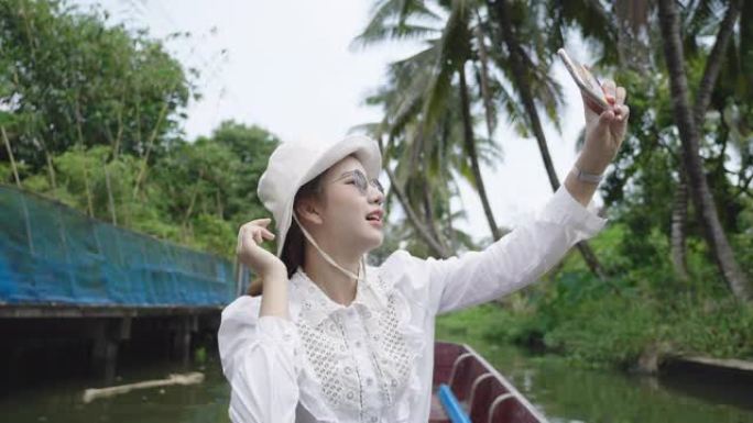 女人在度假泰国计程车船上戴帽子拍照