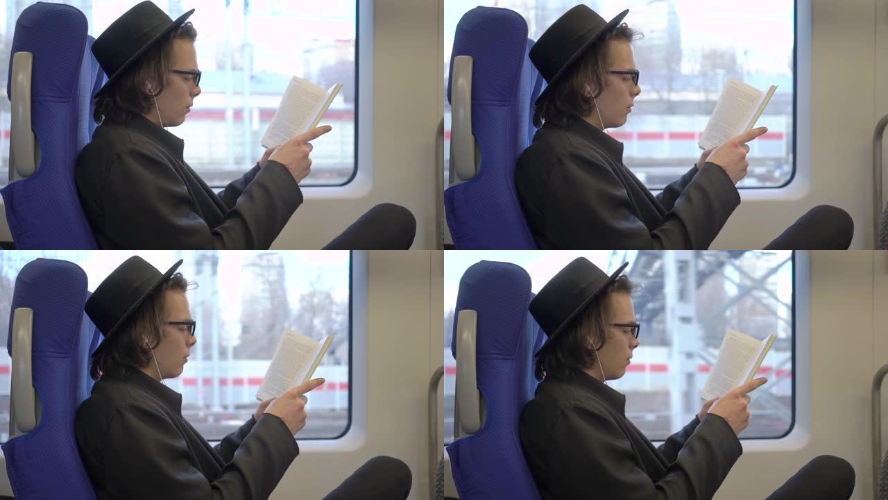 年轻英俊的时尚男子戴着黑帽子和眼镜坐在公共交通工具上看书，千禧一代的时髦学生喜欢在地铁里读书