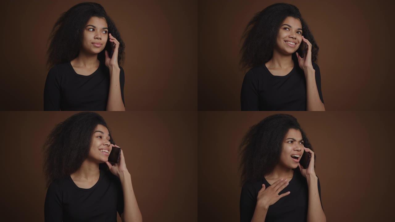 情绪激动的非洲裔美国女孩通过手机聊天棕色背景