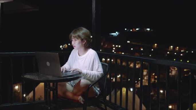 穿着浴袍的女人晚上在酒店套房使用笔记本电脑