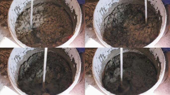建筑工人用水搅拌混凝土，用于建筑。关闭砂浆桶中的混合水泥