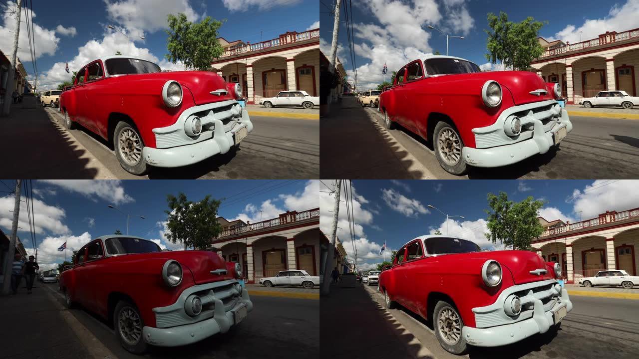 红色复古经典美国汽车停在古巴街头，背景是国旗