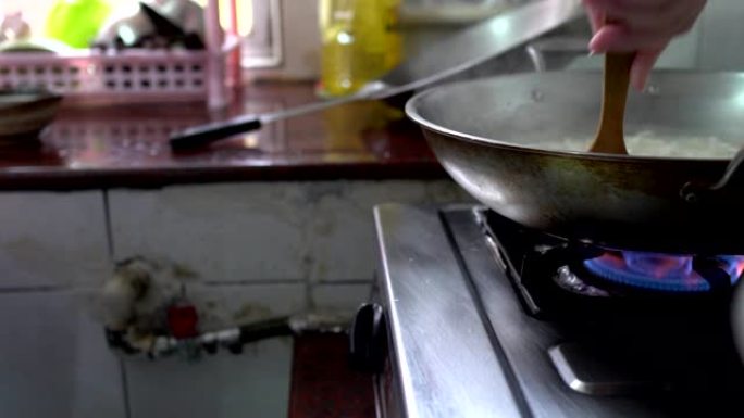 妈妈在锅里用抹刀搅拌。在厨房里使用煤气炉。
