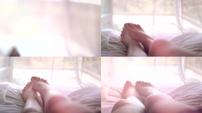 一个女人的脚躺在床上，夏日的阳光照进房间