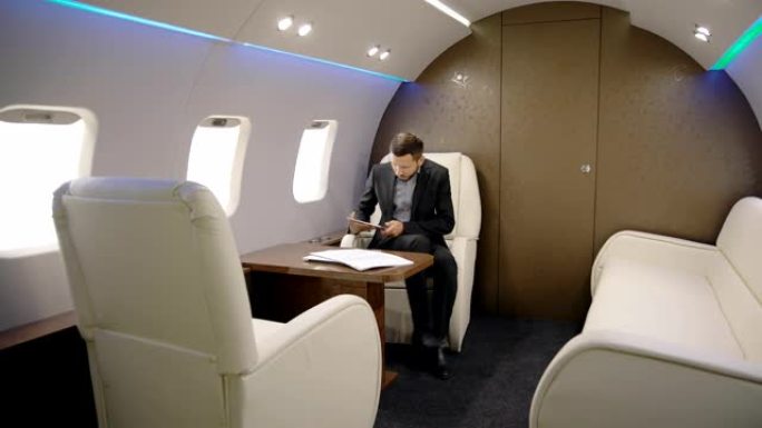 优雅的投资者专家分析师商人正在花时间坐在私人飞机上的平板电脑上