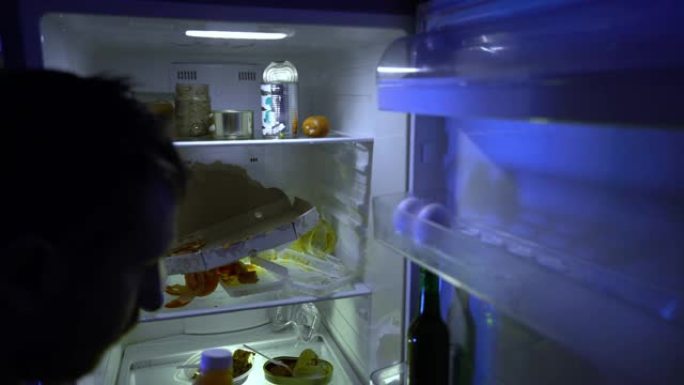 在冰箱里找食物的人。那家伙把剩下的食物放在冰箱里，然后拿了一瓶啤酒。