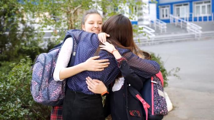 一位快乐的母亲在学校遇到了两个女儿。妈妈拥抱和亲吻穿着校服的孩子。
