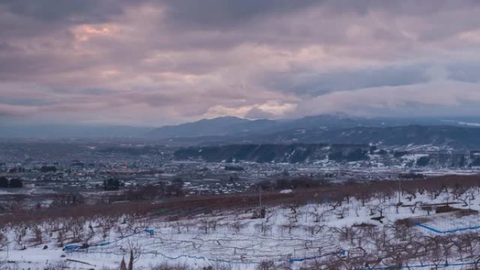 日本长野，冬季中野市的延时鸟瞰图，苹果树在日落时的前景