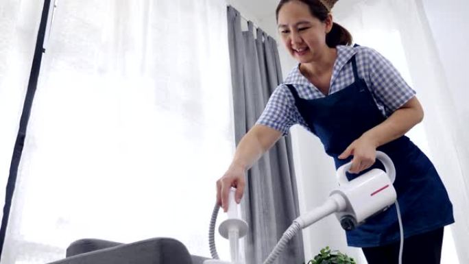 慢动作拍摄亚洲妇女清洁沙发与蒸汽蒸汽清洁器，家庭主妇清洁屋良好的家庭保健