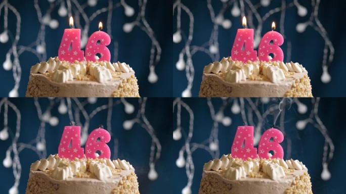 蓝色背景上有46号粉色蜡烛的生日蛋糕。蜡烛吹灭了。慢动作和特写视图