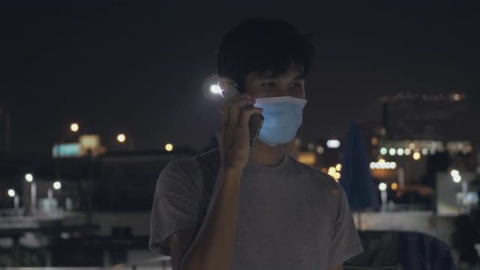 男子使用保护面罩保护新型冠状病毒肺炎病毒，并在城市背景中使用智能手机。