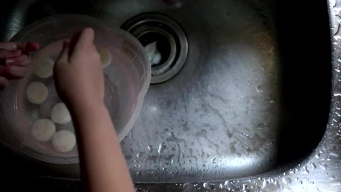 小女孩在厨房洗扇贝。观点。看过去。