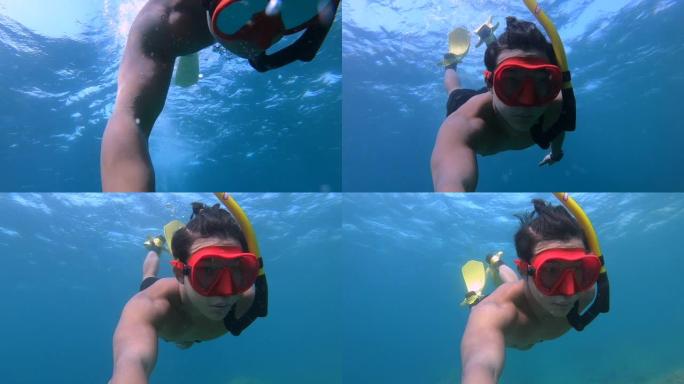 穿着红色潜水镜的亚洲年轻人在水面上，自由潜水，在海洋中央，浮潜晴天，水下镜头，清澈的水，旅行冒险探索