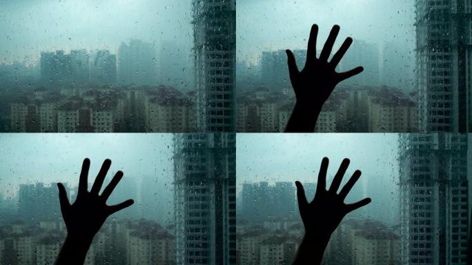剪影女人手触摸玻璃窗有水雨滴